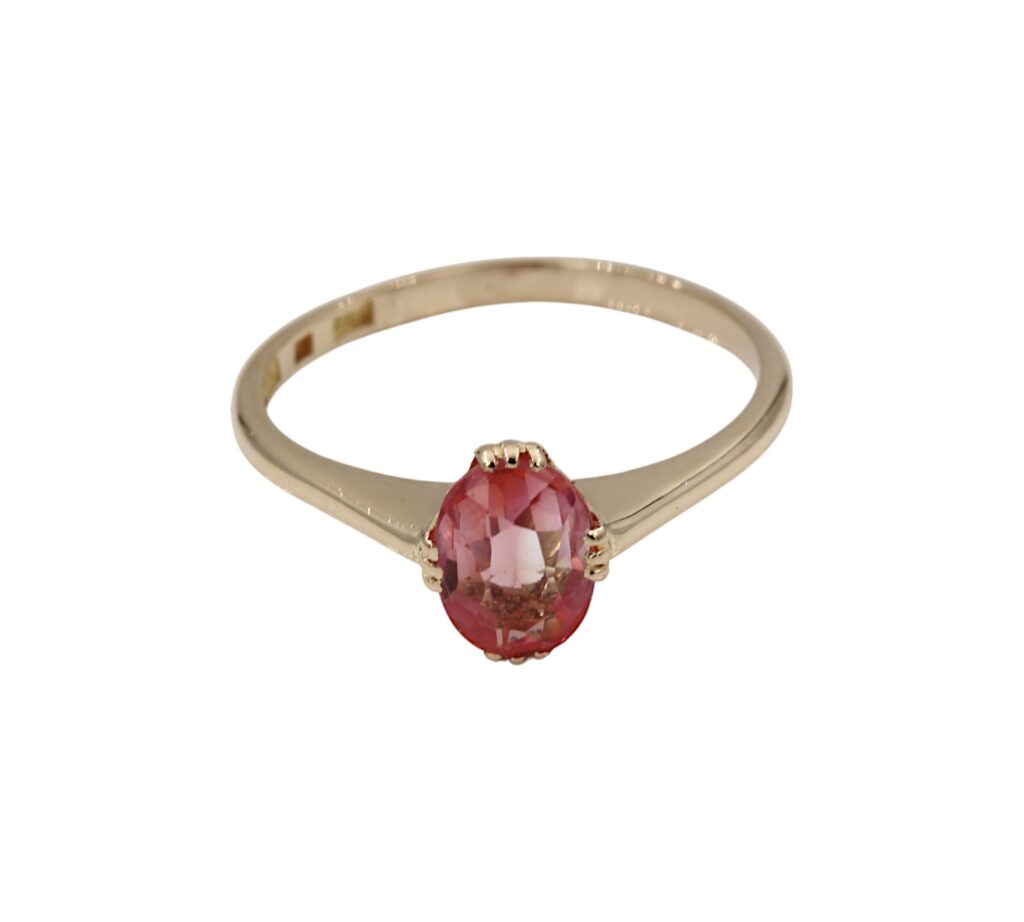 Ring i 18K guld med en rosa/röd sten